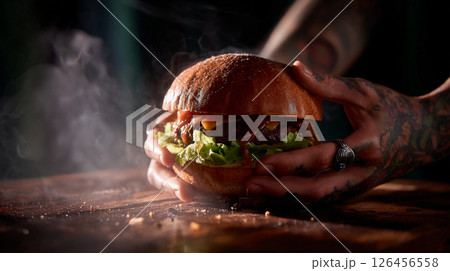 tasty juicy fast food burger in the hands of a brutal man with tattoos for a restaurant menu 126456558