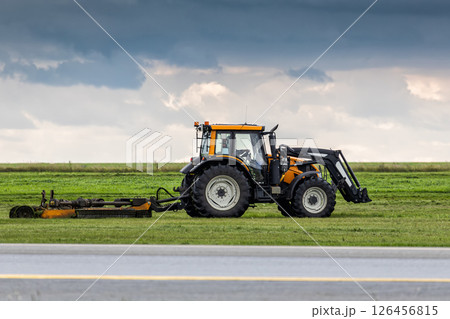 Wheel tractor with lawn mower working by the road Wheel tractor with lawn mower working by the road 126456815