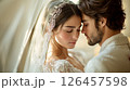 A romantic moment between a bride and groom captured indoors during their wedding celebration in soft, warm lighting 126457598