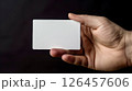 A person holding a blank card with one hand against a dark background in a minimalist setting for emphasis on simplicity and focus 126457606