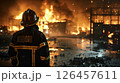 Firefighter observes a raging fire consuming a warehouse at night in an urban setting 126457611