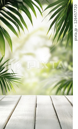 Green palm leaves frame bright, bokeh background with white wooden planks in foreground, perfect for a tropical-themed display or product mockup Green palm leaves frame bright, bokeh background with white wooden planks in foreground, perfect for a tropical-themed display or product mockup 126457720