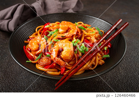 udon stir-fry shrimp noodles with red bell pepper and green onion, served in a black bowl, with chopsticks, dark background, udon stir-fry shrimp noodles with red bell pepper and green onion, served in a black bowl, with chopsticks, dark background, 126460466