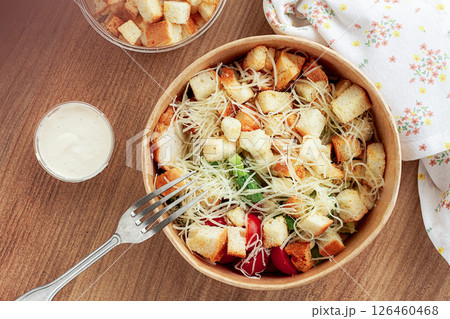 Caesar salad in a paper container, take it on the way, with sauce and croutons, on the table, snack, no people, Caesar salad in a paper container, take it on the way, with sauce and croutons, on the table, snack, no people, 126460468