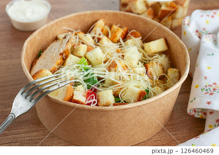 Caesar salad in a paper container, take it on the way, with sauce and croutons, on the table, snack, no people, Caesar salad in a paper container, take it on the way, with sauce and croutons, on the table, snack, no people, 126460469