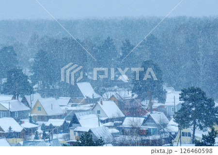 Snowfall blankets a quiet village in the winter season, creating a serene atmosphere and enchanting landscape 126460598