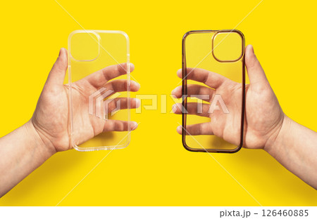 Hands holding two transparent phone cases, one clean and one dirty against bright yellow backdrop. Comparison of new and old smartphone cases. Hands holding two transparent phone cases, one clean and one dirty against bright yellow backdrop. Comparison of new and old smartphone cases. 126460885