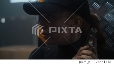 Close Up of Female Secret Agent Hiding Behind Cover in Dark Office Building, Holding a Pistol 126461518