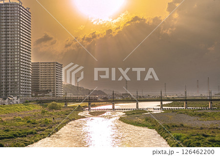 夕日に照らされるマンション群と多摩川を渡る京王線の電車の写真 夕日に照らされるマンション群と多摩川を渡る京王線の電車の写真 126462200