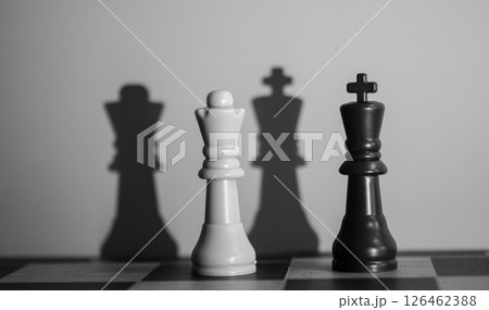 Chess Queen and King Casting Dramatic Shadows: Symbolism of Power, Strategy, and Contrast 126462388