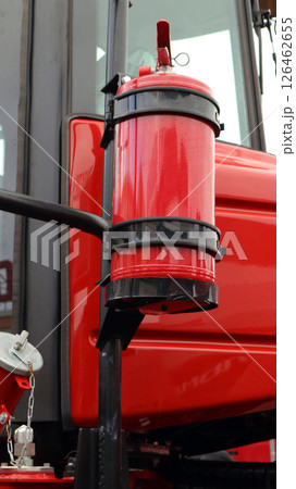 A fire extinguisher is securely mounted on the side of agricultural machinery, ensuring quick access for fire safety during farming activities in a rural location. A fire extinguisher is securely mounted on the side of agricultural machinery, ensuring quick access for fire safety during farming activities in a rural location. 126462655