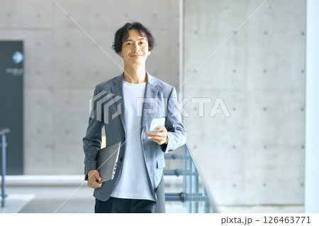 オフィスでスマホを操作するビジネスカジュアルの男性エンジニア 126463771