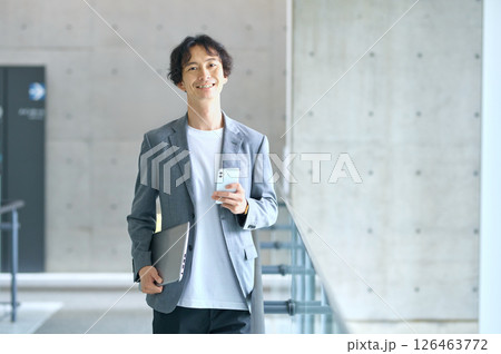 オフィスでスマホを操作するビジネスカジュアルの男性エンジニア 126463772