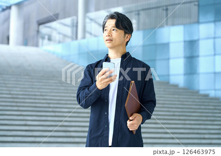 オフィスでスマホを操作するビジネスカジュアルの男性エンジニア 126463975