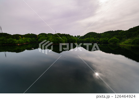 薄曇りの空のもと次第に沈んでいく太陽とシンメトリーで動く湖面に映った太陽　奈良市布目ダムにて⑤ 126464924