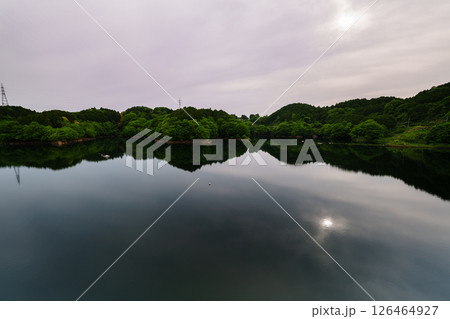 薄曇りの空のもと次第に沈んでいく太陽とシンメトリーで動く湖面に映った太陽　奈良市布目ダムにて⑧ 126464927