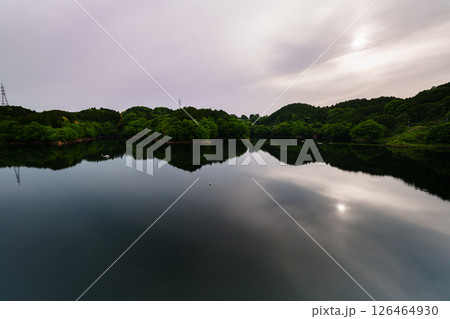 薄曇りの空のもと次第に沈んでいく太陽とシンメトリーで動く湖面に映った太陽　奈良市布目ダムにて⑪ 126464930