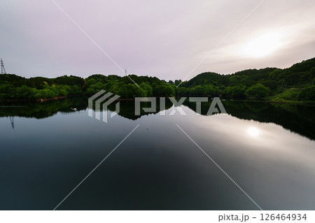 薄曇りの空のもと次第に沈んでいく太陽とシンメトリーで動く湖面に映った太陽　奈良市布目ダムにて⑮ 126464934