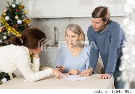 Man and woman help elderly mother make will and fill out document correctly On Christmas Eve 126464993