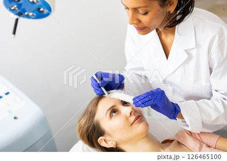 Beautician drawing correction lines on woman face 126465100