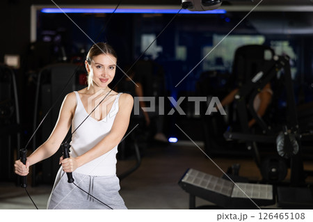 Active athlete young woman during exercises on crossover exercise machine with loops and weighting Active athlete young woman during exercises on crossover exercise machine with loops and weighting 126465108