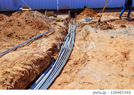 Many electrical conduits are being installed in trench at construction site emphasizing industrial Many electrical conduits are being installed in trench at construction site emphasizing industrial 126465348