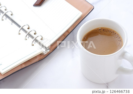 ミルクをたっぷり入れたコーヒー、カフェ・ラッテを飲みながら、日記をつけているイメージ 126466738