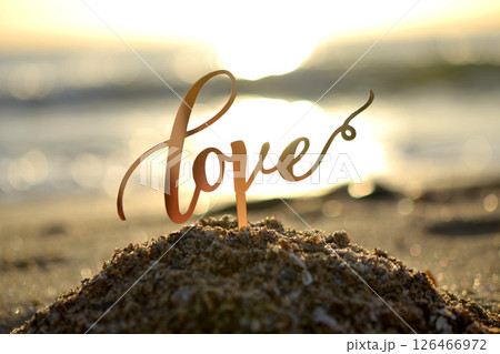 Outlines of word Love at dawn and sunset on background of sea waves on seashore. Stick contours in shape word Love in sand of setting and rising sun. Concept Love infatuation Valentine's Day Outlines of word Love at dawn and sunset on background of sea waves on seashore. Stick contours in shape word Love in sand of setting and rising sun. Concept Love infatuation Valentine's Day 126466972