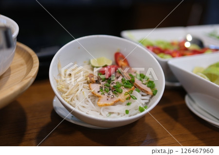 ingredients for vietnamese pho bo soup. bowl with chopsticks, spoon. Space for text. Top view. Asian soup Pho bo on wooden table background. Vietnamese soup ingredients for vietnamese pho bo soup. bowl with chopsticks, spoon. Space for text. Top view. Asian soup Pho bo on wooden table background. Vietnamese soup 126467960