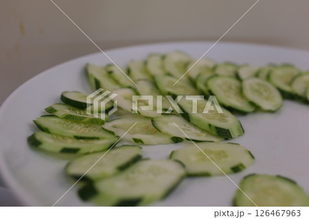 sliced cucumbers rotating on black plate, centered with strong reflection  126467963