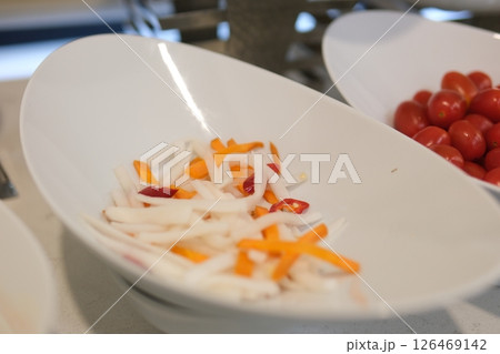 carrot radish slices of fresh peeled carrots and daikon radishes, half of unpeeled daikon radishes lie on white table. Carrot, daikon radishes, popular ingredients in vegetable salads and snacks carrot radish slices of fresh peeled carrots and daikon radishes, half of unpeeled daikon radishes lie on white table. Carrot, daikon radishes, popular ingredients in vegetable salads and snacks 126469142