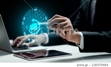 Businessman using a laptop and showing a cargo truck icon on the tablet screen. Laptop on the desk. Technology innovation on the virtual screen. Concept of industry, transport, and logistics 126470464