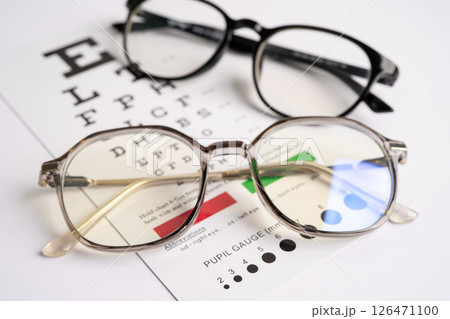 Glasses on eye testing exam chart to check eyesight accuracy of reading. 126471100