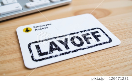 Employee access card marked with "LAYOFF" on a wooden desk. Employee access card marked with "LAYOFF" on a wooden desk. 126471281