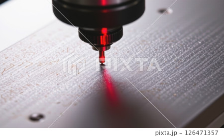Precision tool in action on a metal surface with a red laser guide. 126471357