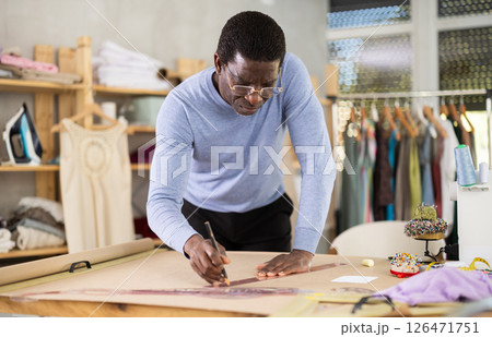 African American man tailor draw dress pattern of product on paper African American man tailor draw dress pattern of product on paper 126471751