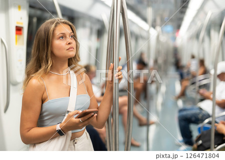 Young woman is standing in subway car with phone, getting to work school. 126471804