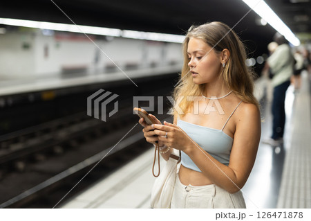 Young girl standing in platform with phone in hand Young girl standing in platform with phone in hand 126471878