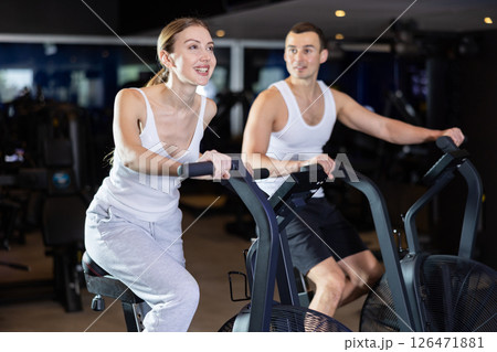 During classes on air bike, girl and man chat sweetly and smile 126471881