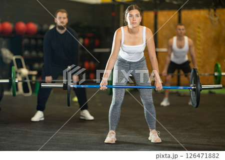 Sportive young woman lifting barbell in sports hall 126471882