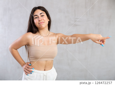 Young woman pointing aside standing against the wall Young woman pointing aside standing against the wall 126472257