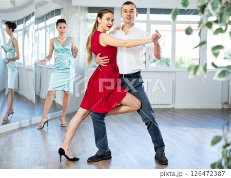 Couple in stage costumes learns tango dancing during individual lesson Couple in stage costumes learns tango dancing during individual lesson 126472387