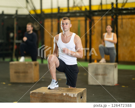 Sportive young guy doing step-up exercises with box during crossfit workout 126472388