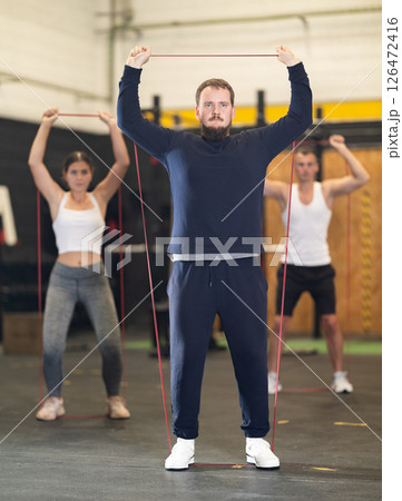 Motivated bearded guy doing exercises with elastic loop band in gym 126472416