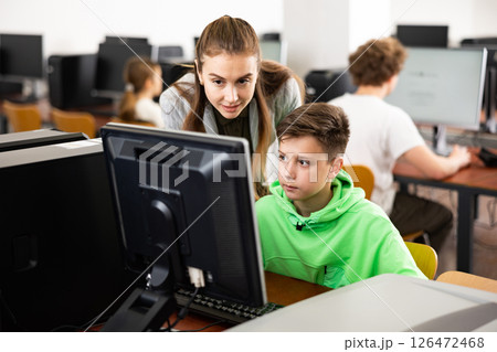 Female teacher consulting tween boy studying in computer class 126472468