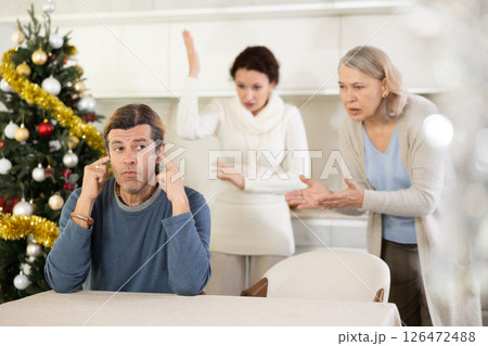 Elderly mother and woman during family quarrel accuse adult man on Christmas Eve 126472488