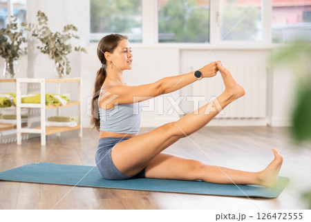 Lover of active lifestyle on yoga mat perform doing eka padahastasana salamba navasan in gym 126472555