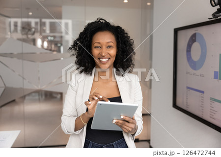 Project manager using tablet standing next to screen displaying charts Project manager using tablet standing next to screen displaying charts 126472744