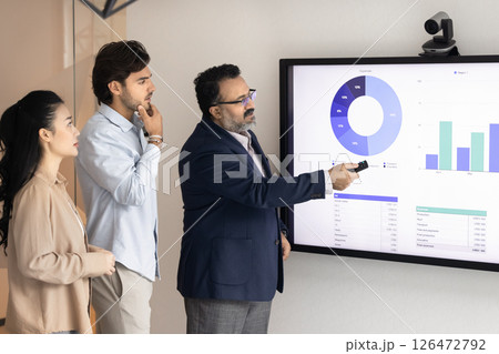 Male professional presenting financial data on digital screen to colleagues Male professional presenting financial data on digital screen to colleagues 126472792