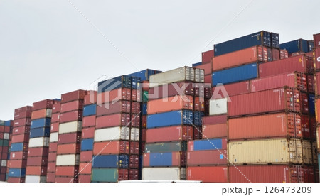 Stacked shipping containers in varying colors against a gray sky. Stacked shipping containers in varying colors against a gray sky. 126473209